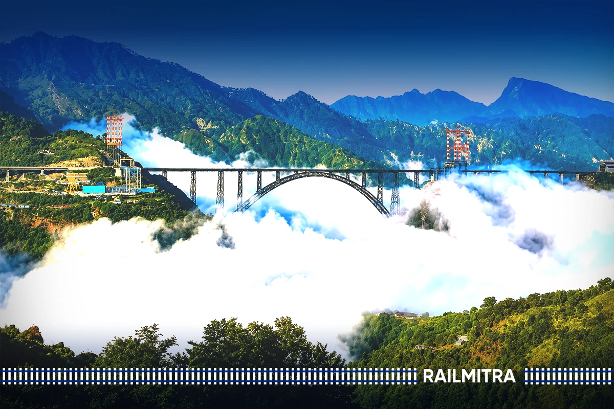 Panoramic view of the Chenab Bridge emerging through a thick sea of white clouds nestled amidst green Himalayan mountains.